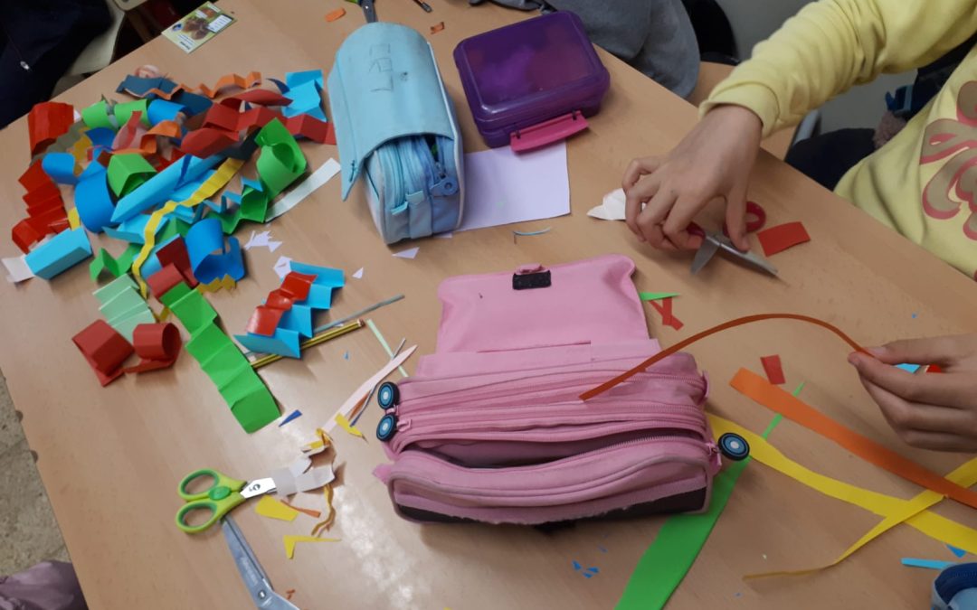 Nens, nenes i adolescents del SIS d'Aiguafreda amb tot d'elements damunt la taula per pintar la cara i fer materials pel Carnaval.