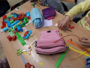 Nens, nenes i adolescents del SIS d'Aiguafreda amb tot d'elements damunt la taula per pintar la cara i fer materials pel Carnaval.